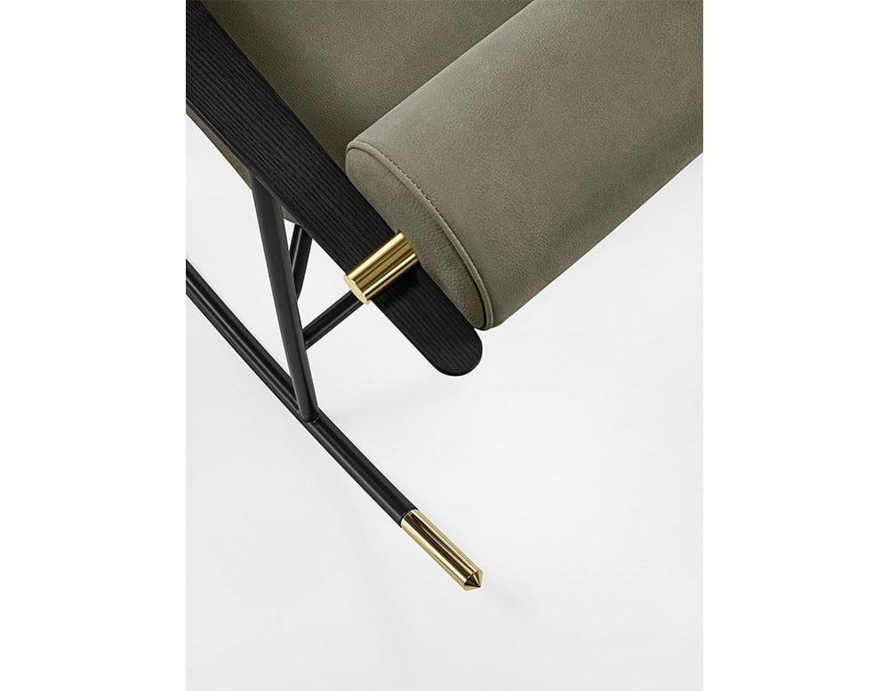 Lou Lou Rock Chair detail close-up. The shot highlights the olive green upholstery, black ash wood armrest, and polished brass accents on the rocking frame against a clean white background.