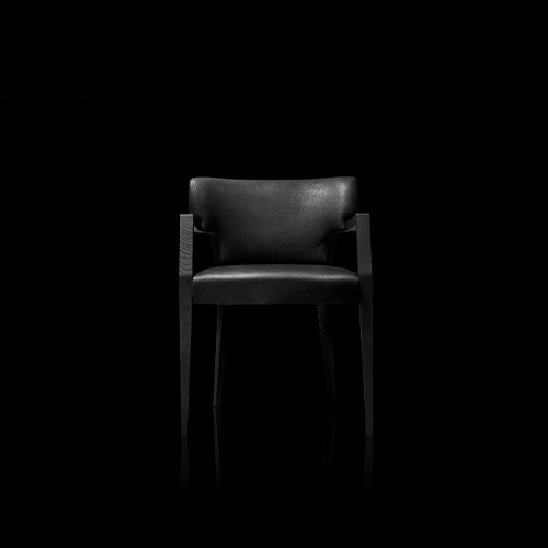A refined silhouette with bold stance, this armchair balances sculpted wood and tailored leather to offer comfort and architectural elegance in equal measure.