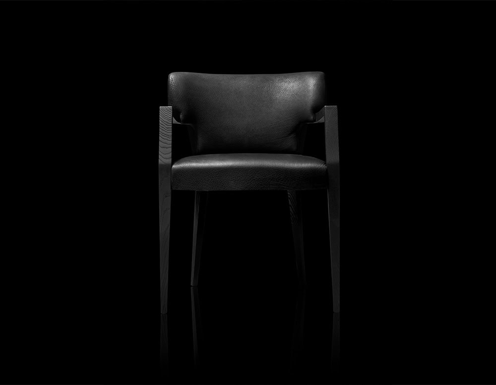 Refined and bold, this armchair features a sculpted solid wood frame with a soft, curved leather seat and backrest. The contrast between sharp angles and plush textures creates a timeless presence.