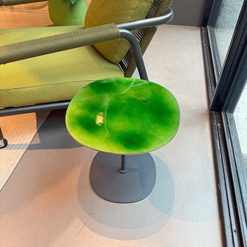 Vibrant green enamel side table with a rounded top and slender metal base. Its glossy finish adds energy to modern indoor or outdoor spaces.