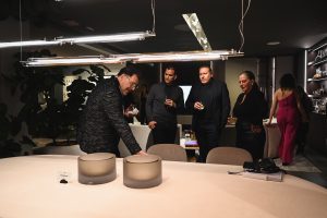 uests gather around a display as one attendee highlights the craftsmanship up close creating a relaxed moment of curiosity and conversation in the elegant showroom atmosphere.