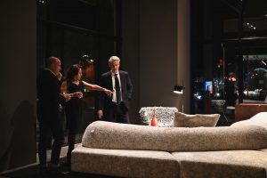 Guests take a closer look at one of the showroom’s standout sofas, sharing impressions as the warm lighting and refined atmosphere highlight every detail of the design.