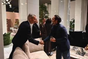 Guests connect over friendly handshakes in the heart of the showroom, surrounded by elegant furniture and soft lighting that sets the tone for an inviting and stylish evening.