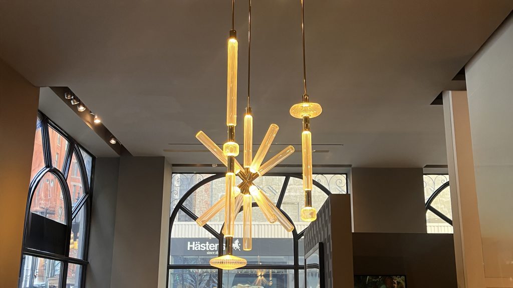 Cipher suspension by Lasvit featuring elongated handblown glass elements arranged in a radiant composition with warm amber illumination highlighting the refined craftsmanship geometric rhythm and sculptural elegance of the lighting piece.