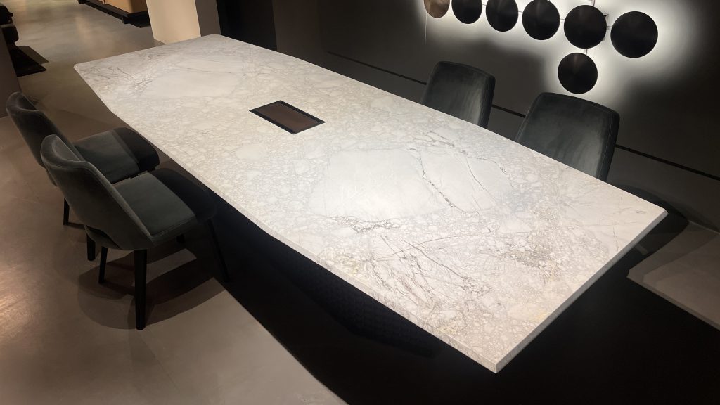 S Penny dining table featuring a light marble surface with subtle veining paired with a sculptural dark base creating a refined contrast of soft stone tones and deep charcoal accents ideal for modern and elegant dining interiors.