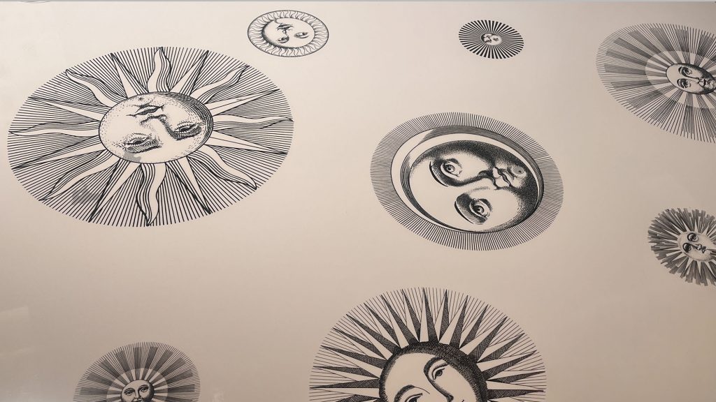 Detail of the Soli e Lune tabletop by Fornasetti featuring finely illustrated sun and moon faces rendered in monochrome tones creating a poetic celestial pattern that reflects the brand’s surreal and timeless artistic language.