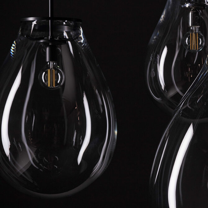 A refined pendant light with a clear teardrop glass shade and visible filament bulb. The dark metal detailing enhances its elegant silhouette, while the transparent form creates a soft, atmospheric glow in modern interiors.