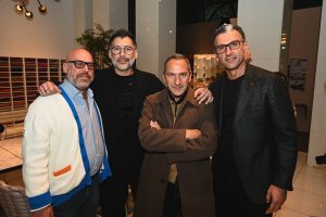 Four guests pose together in a sophisticated showroom setting, blending contemporary fashion, warm conversation, and an elegant evening event atmosphere.