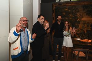 Guests share a lively moment at the evening gathering, surrounded by artful interiors, warm lighting, and an energetic social atmosphere.