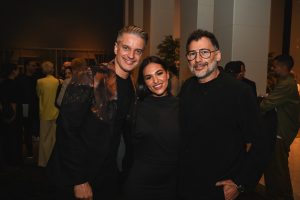 A stylish trio poses during the evening celebration, bringing together bold fashion, warm smiles, and contemporary elegance in a lively social setting.