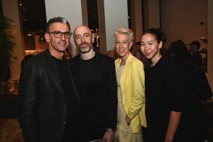 Four guests pose together at a sophisticated evening gathering, blending modern fashion, warm conversation, and an elegant social atmosphere.