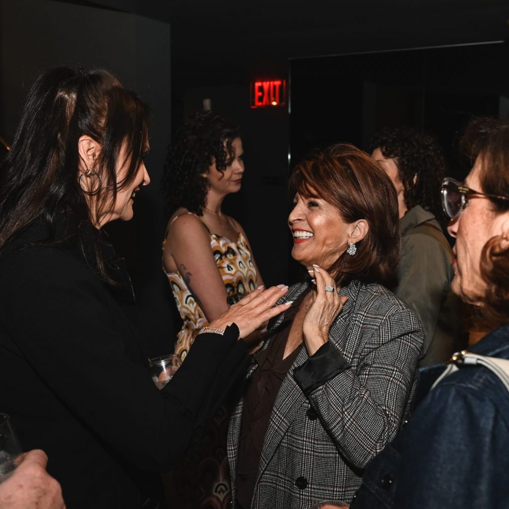 Guests share a joyful conversation during the evening gathering, enjoying meaningful connections in an intimate and sophisticated showroom atmosphere.