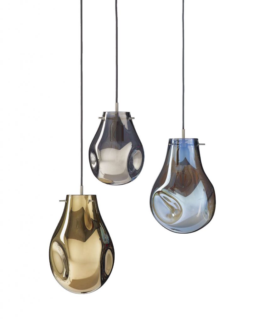 The pendant lights feature hand blown glass shades in amber, smoky gray, and soft blue, each with a rounded organic form. Suspended individually, they highlight the fluid character of the glass while casting a warm, inviting glow.