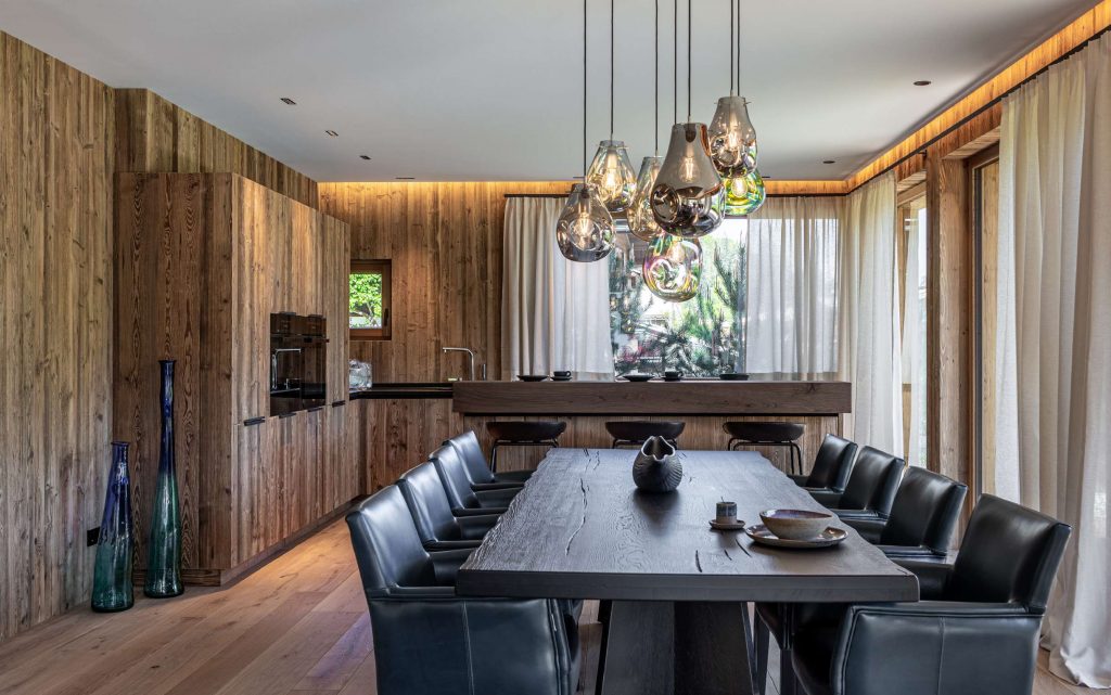 The pendant lights create a sculptural focal point above the dining table, with hand blown glass shades in smoky and iridescent finishes. Suspended at varying heights, they bring warmth, depth, and a refined contemporary presence to the space.